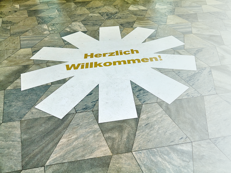 Boden im Opernfoyer mit dem Bühnen-Halle-Logo in Weiß und der Aufschrift "Herzlich Willkommen!"