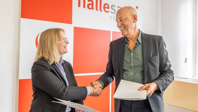 Dr. Judith Marquardt und Klaus Dörr reichen sich die Hände bei der Vertragsunterzeichnung.