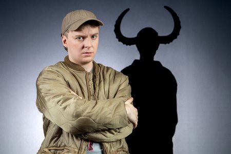 Franz Blumenstock sitzt in Gummistiefeln auf dem Boden. Er guckt verärgert. Im Hintergrund sind Schatten von einem Kind mit Hörnern. © Julia Fenske